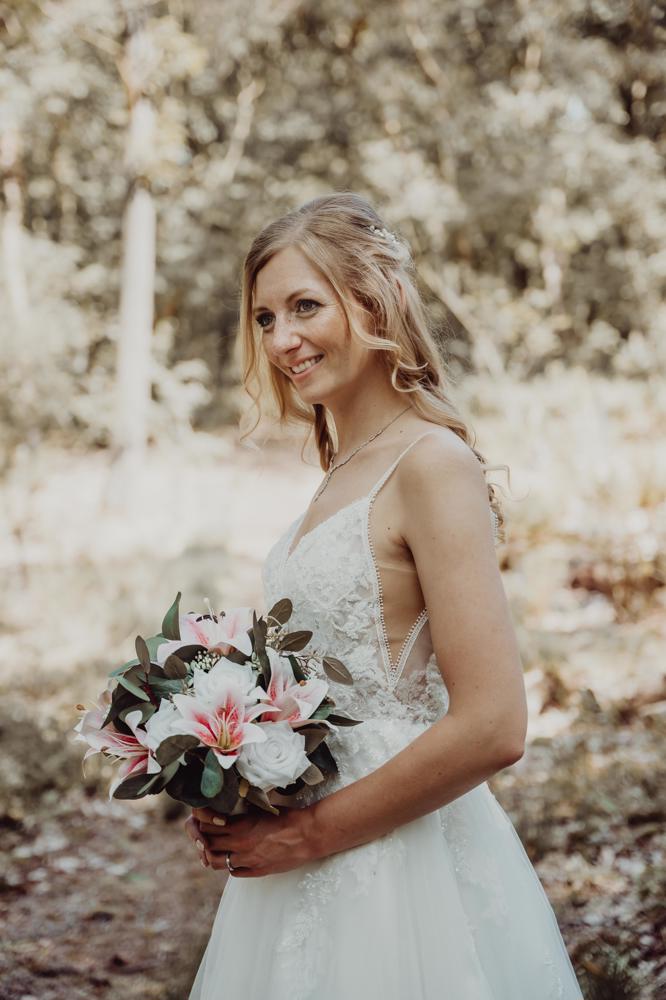 Stralende bruid in kanten trouwjurk met bruidsboeket - Bruidshuis Diana